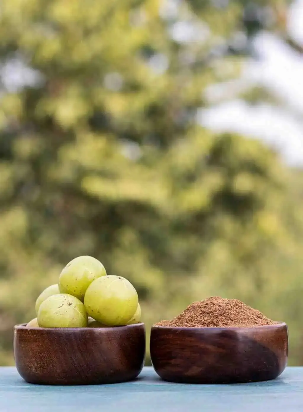 Ayurvedic herbal oil in glass bottle with fresh basil leaves and flowers on yellow background